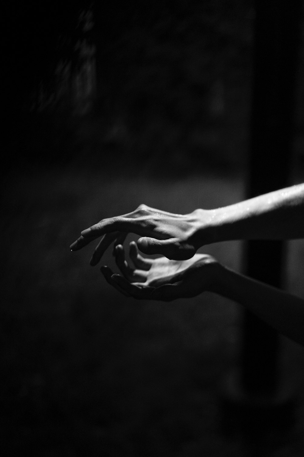 a black and white photo of two hands reaching towards each other