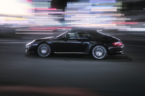 A sleek street car tearing through a city at dusk, lights streaking behind.