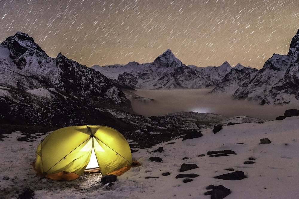 a tent pitched up on a snowy mountain at night