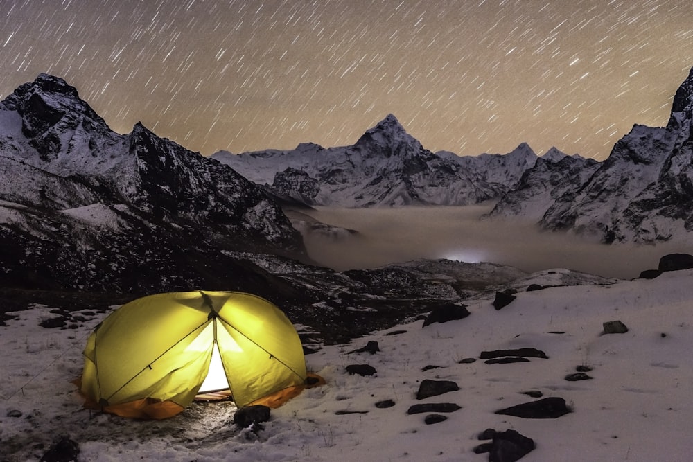 una tenda piantata su una montagna innevata di notte