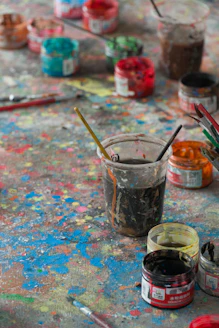 a table topped with lots of paint and brushes