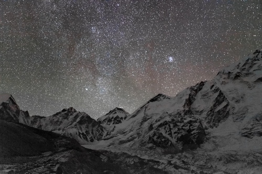 the night sky over a snowy mountain range