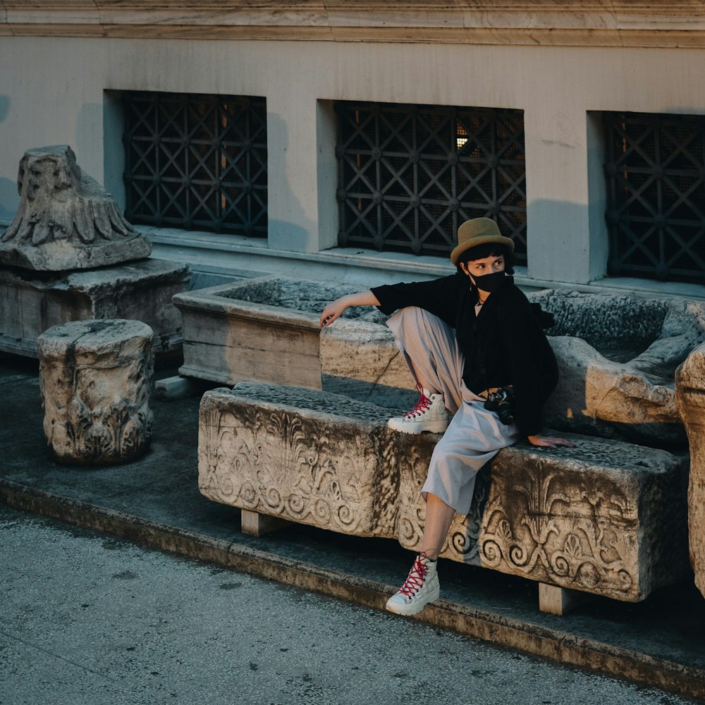 a man sitting on a stone bench in front of a building