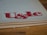 Large, stylized red lettering 'U&lc' on the corner of a page, with the edge of a book in the foreground and a wooden surface underneath.