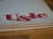 Large, stylized red lettering 'U&lc' on the corner of a page, with the edge of a book in the foreground and a wooden surface underneath.