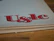 Large, stylized red lettering 'U&lc' on the corner of a page, with the edge of a book in the foreground and a wooden surface underneath.