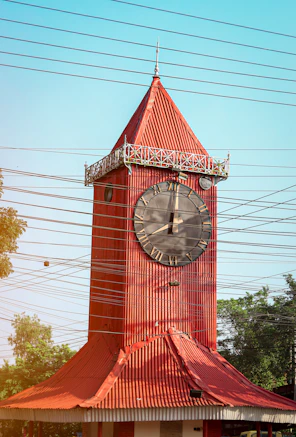 a large red clock tower with a red roof