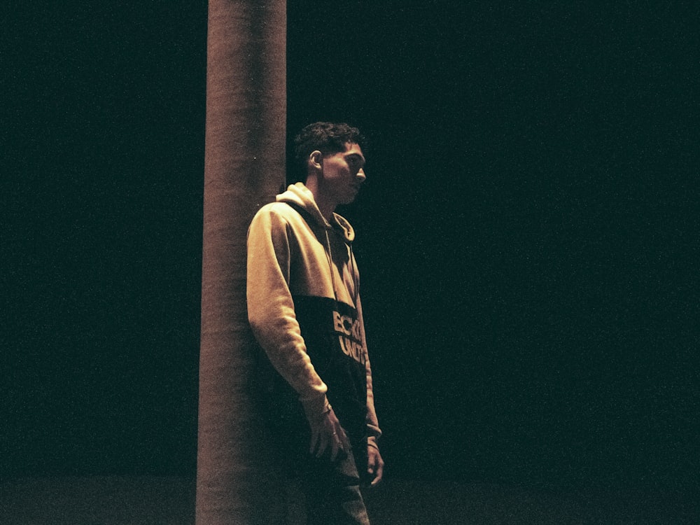 a man leaning against a pillar in the dark