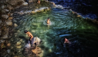 Children and families enjoying crystal-clear pools surrounded by natural rock formations and vibrant flowers.