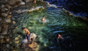 Children laughing and playing in the aquapark pool area surrounded by natural scenery.