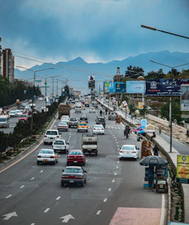 a city street filled with lots of traffic under a cloudy sky