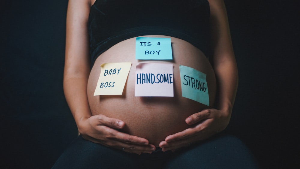 a pregnant woman holding her belly with sticky notes on it