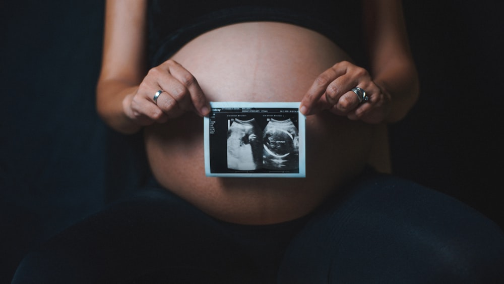 une femme enceinte tenant un appareil photo dans ses mains
