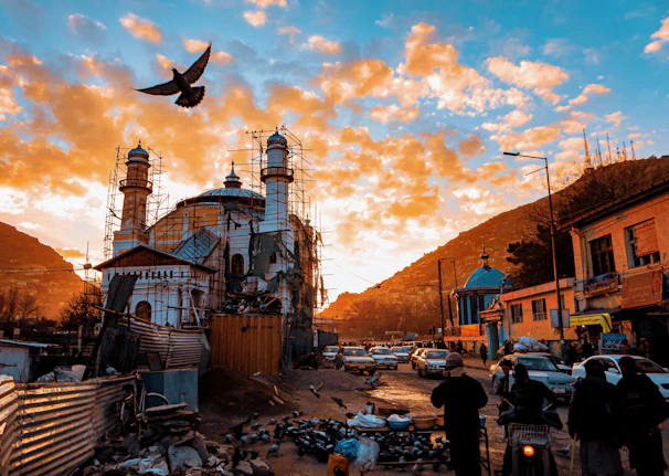 A vibrant photo showing volunteers laying bricks during mosque construction at sunset.