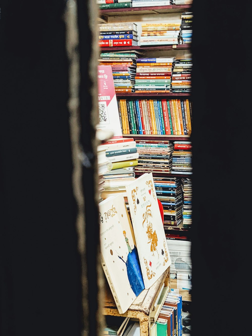 a bookshelf filled with lots of books next to a window