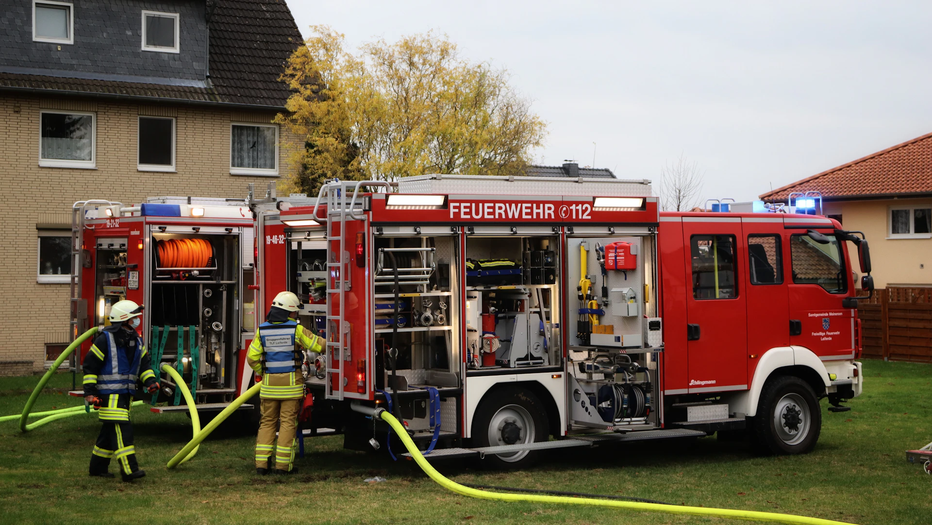 a couple of firemen standing next to a fire truck