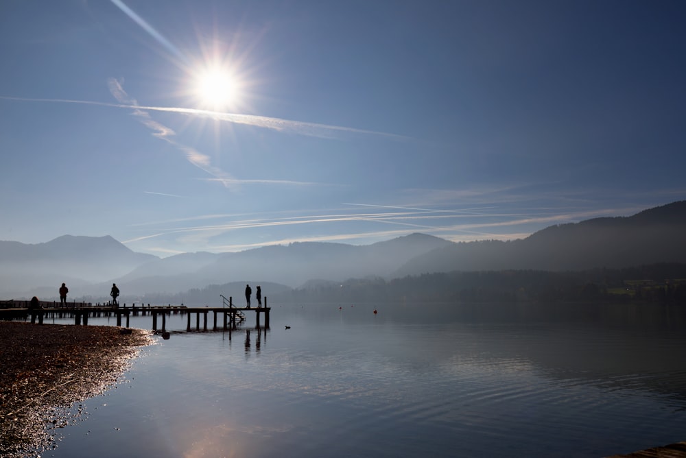 a group of people standing on a pier next to a body of water