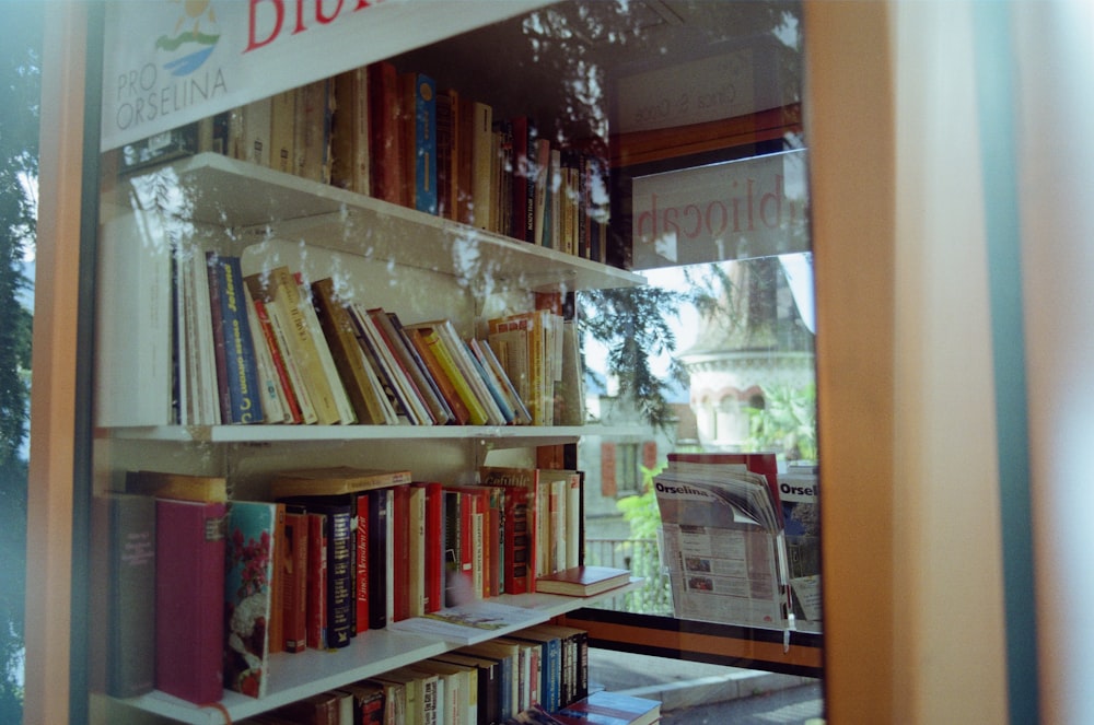 Una estantería llena de muchos libros al lado de una ventana