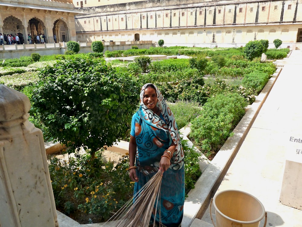 a woman in a blue sari is holding a broom