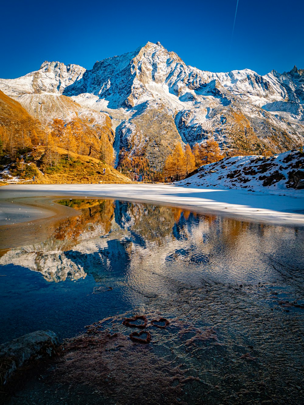 a snow covered mountain with a lake in the foreground