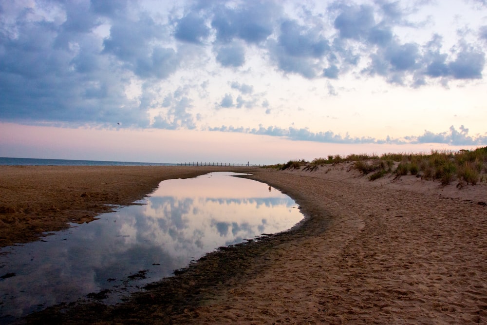 a body of water sitting on top of a sandy beach