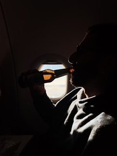 A serene moment capturing the evening light filtering through airport windows as someone relaxes with a cigar and 0% alcohol drink.