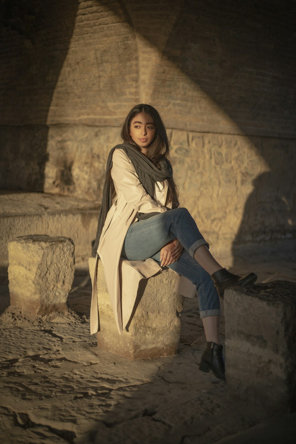 a woman is sitting on a stone bench