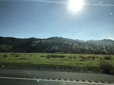 Photograph of a sunny lot near rolling hills and open sky.