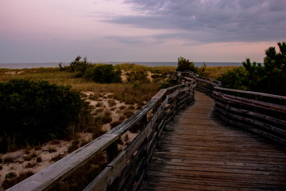 a wooden walkway leading to the beach at dusk