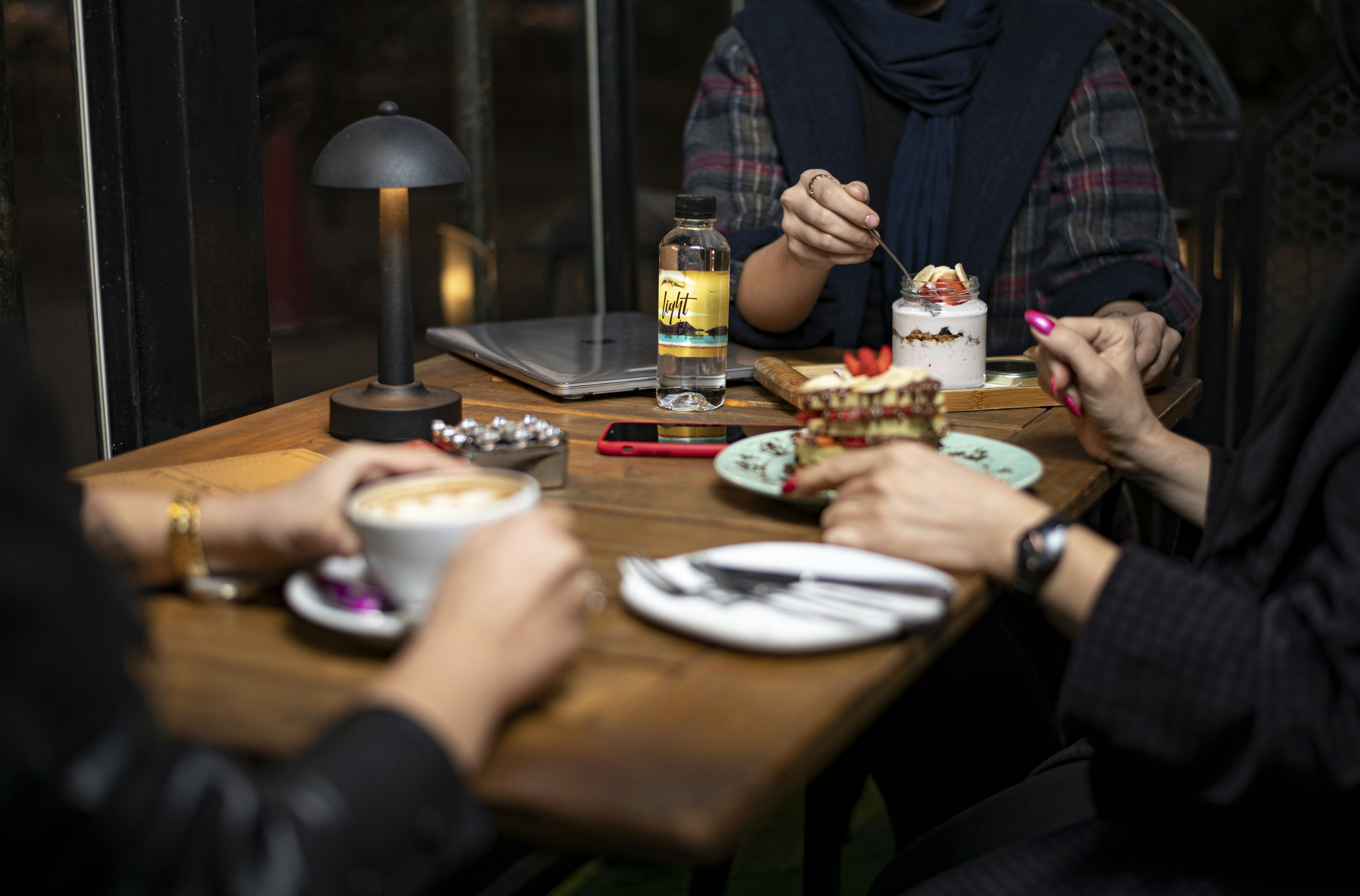 People eating dessert and drinking coffee at a cafe table.