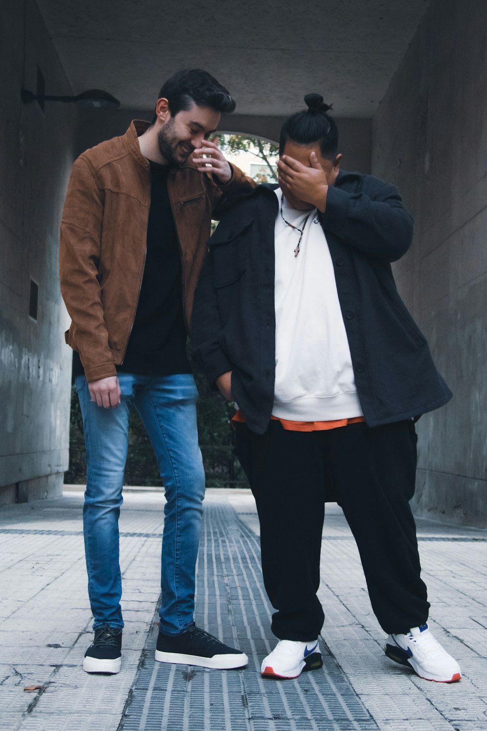 two men standing next to each other on a sidewalk