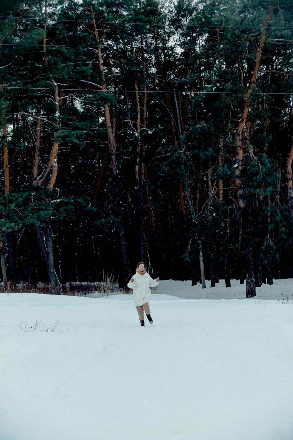 a woman standing in the snow in front of a forest