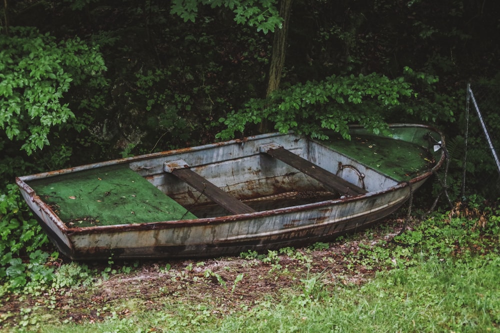 an old rusty boat sitting in the grass