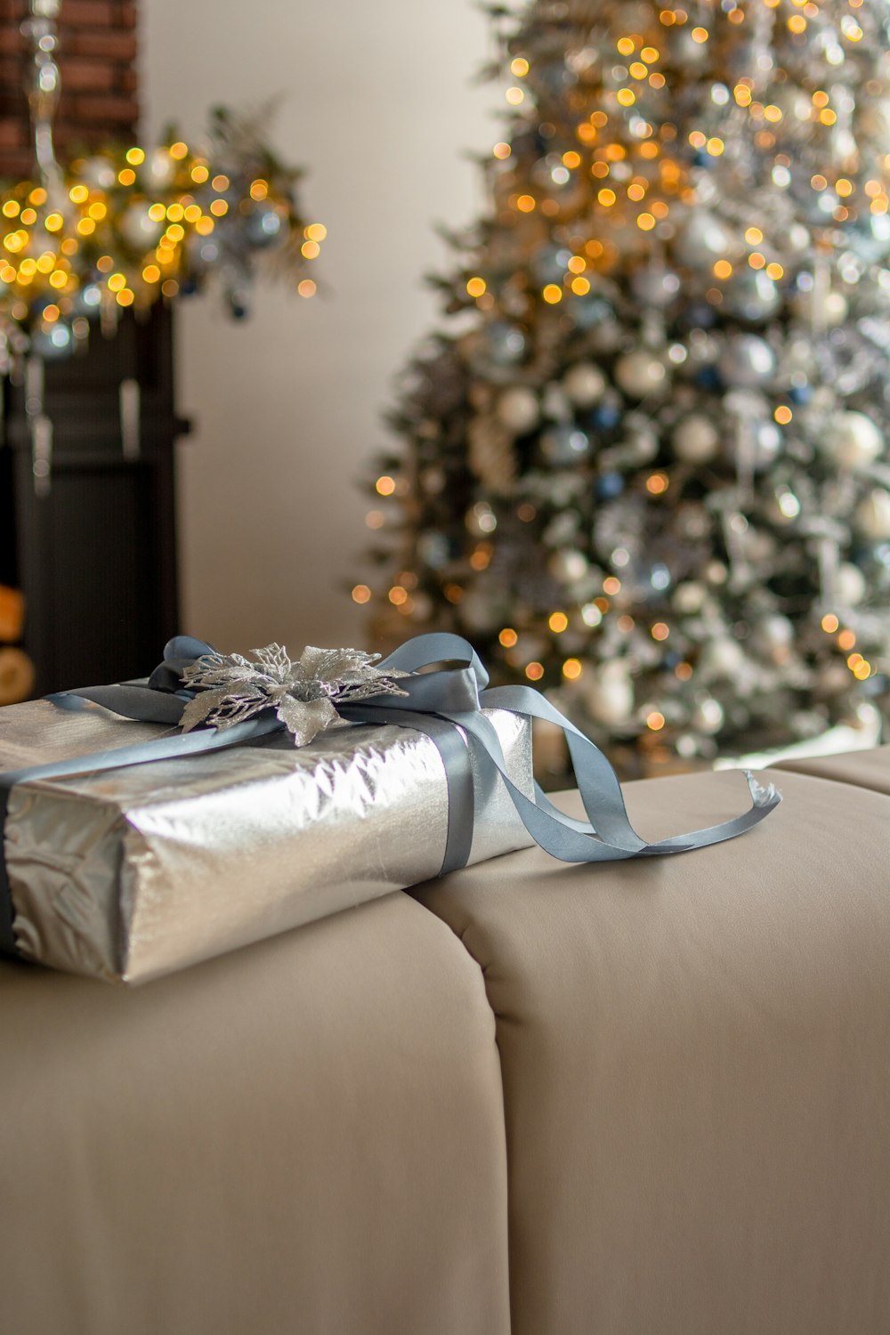 a wrapped present sitting on a couch in front of a christmas tree