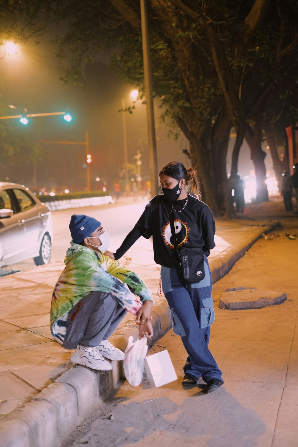 two people standing on a sidewalk at night