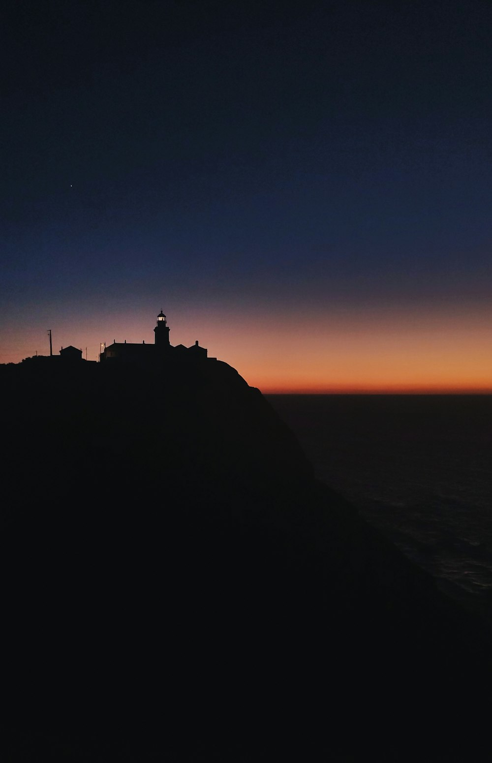 a lighthouse on top of a hill at sunset