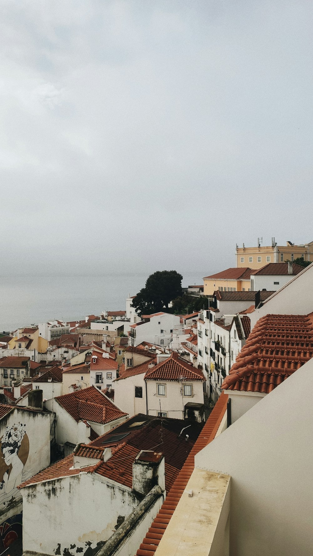 a view of a city with rooftops and a body of water in the distance