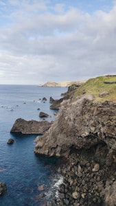 a large body of water sitting next to a lush green hillside