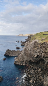 a large body of water sitting next to a lush green hillside