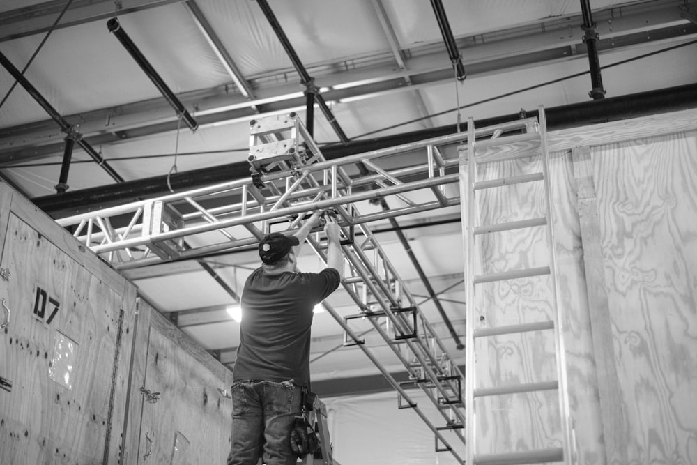 a man standing on a ladder working on a ceiling