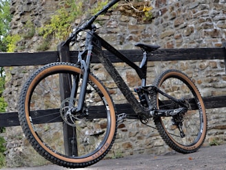 a mountain bike leaning against a wooden fence