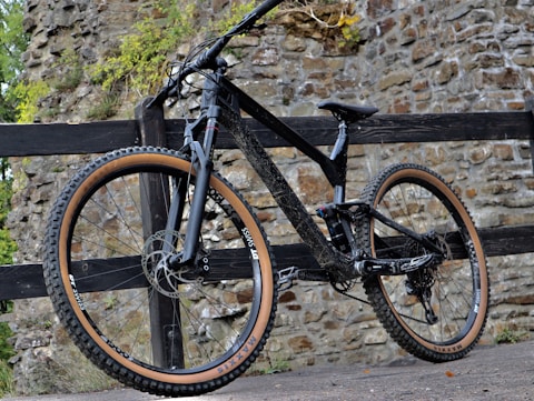 a mountain bike leaning against a wooden fence