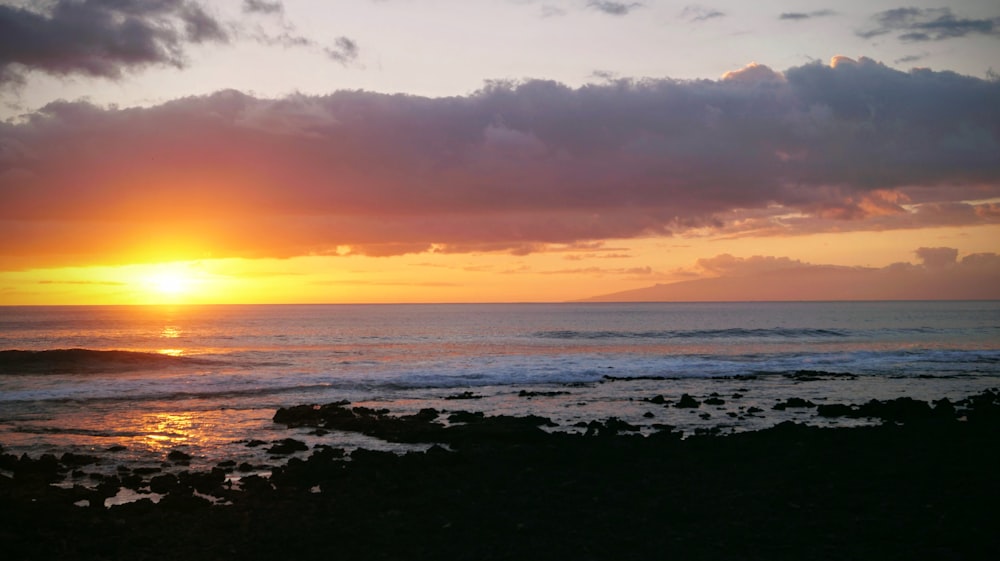 Il sole sta tramontando sull'oceano in una giornata nuvolosa