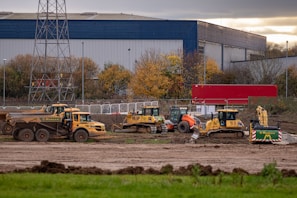 a group of construction vehicles parked in front of a factory
