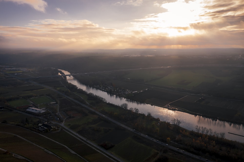 a river running through a lush green countryside under a cloudy sky