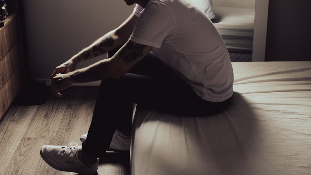 a man sitting on top of a bed next to a dresser