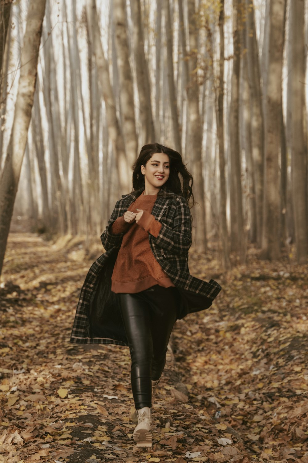 a woman is walking through the woods in the fall