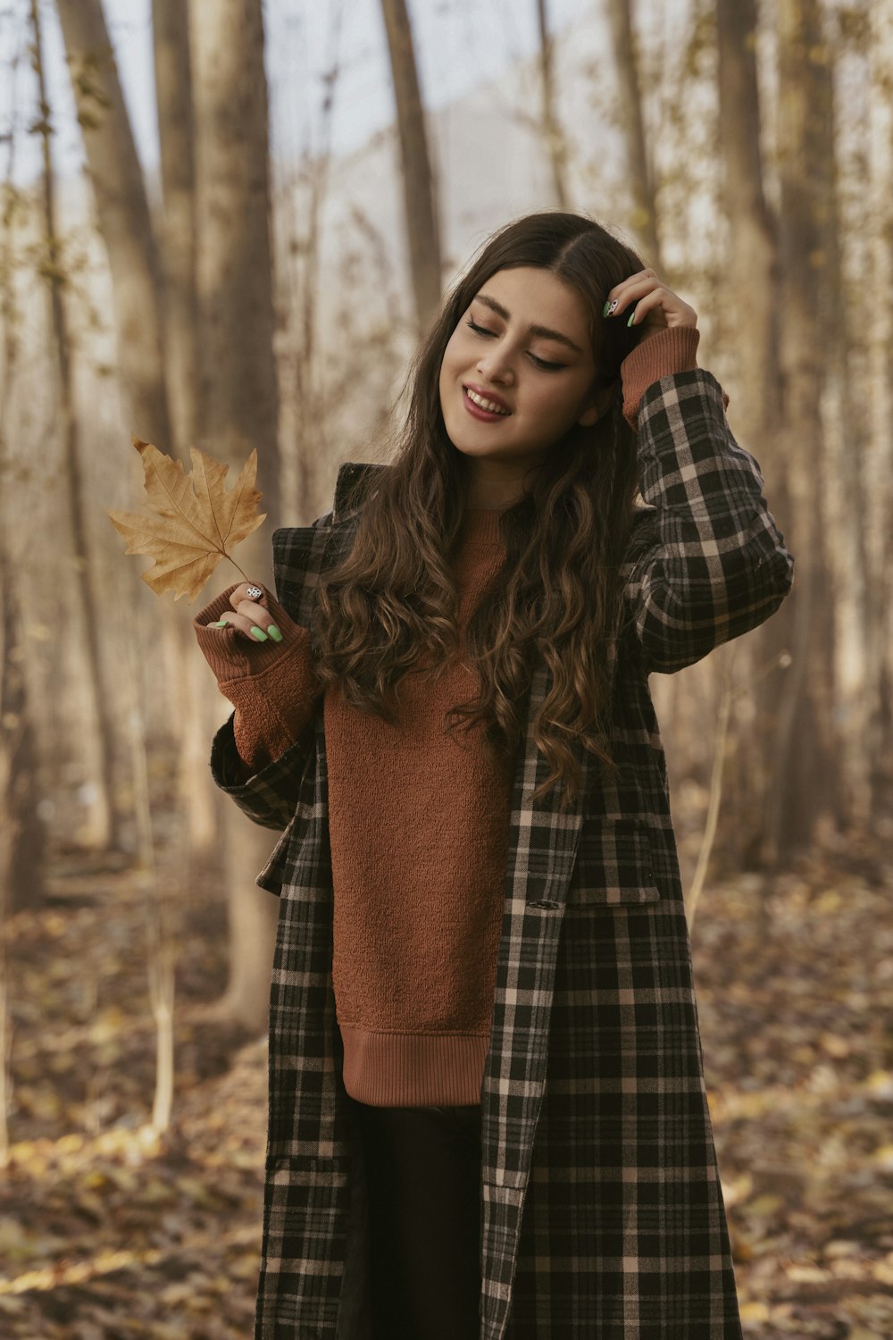 a woman holding a leaf in a forest