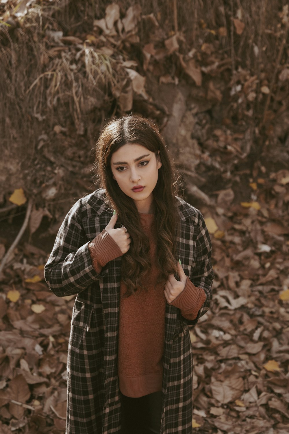 a woman standing in leaves giving the thumbs up