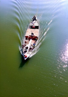 A calm river with a sturdy boat carrying crates of food supplies towards a remote village.